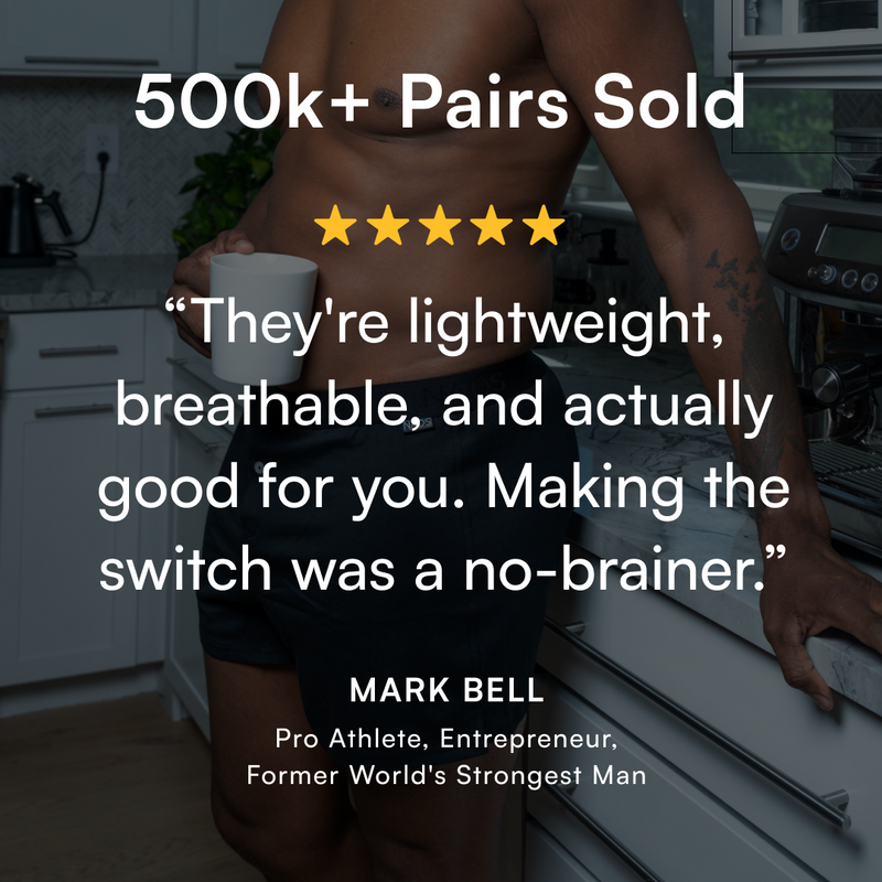 Shirtless man wearing black boxers in a kitchen, holding a coffee mug. Overlay text highlights: ‘500k+ pairs sold, five-star review, lightweight and breathable underwear — testimonial by Mark Bell, pro athlete.’