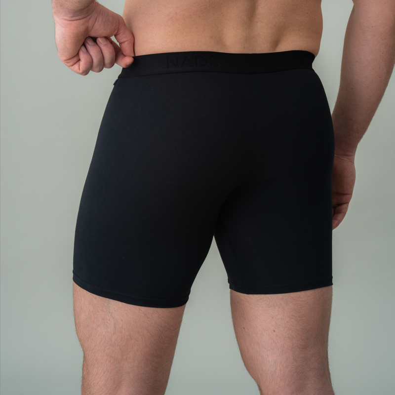 Person wearing black boxer briefs against a plain background