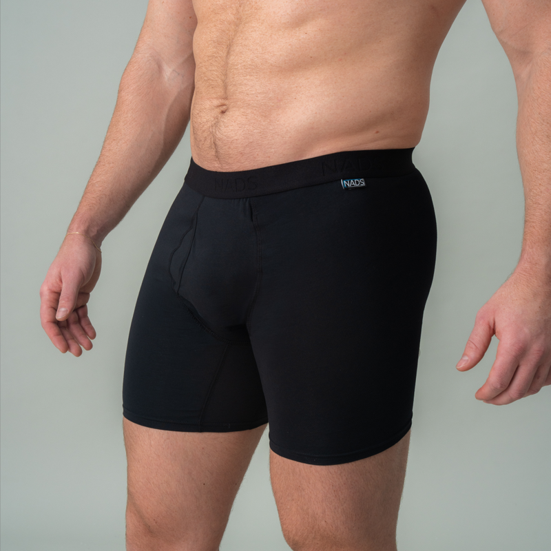 Person wearing black swim shorts on a plain background