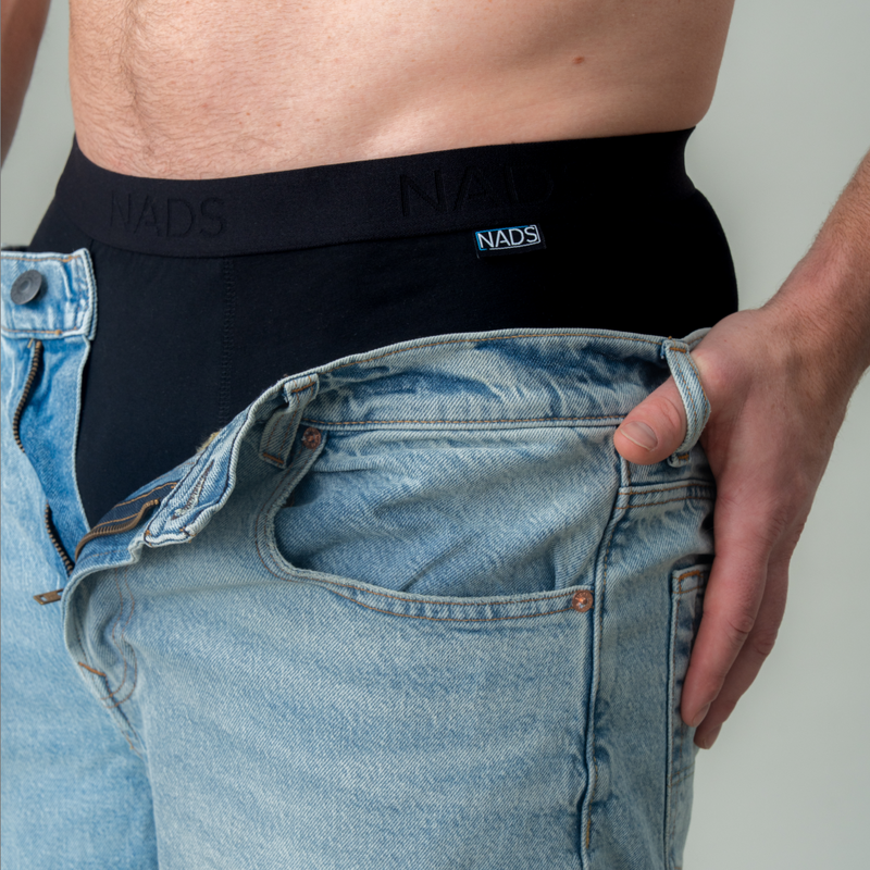 Person wearing black NADS underwear with blue jeans.